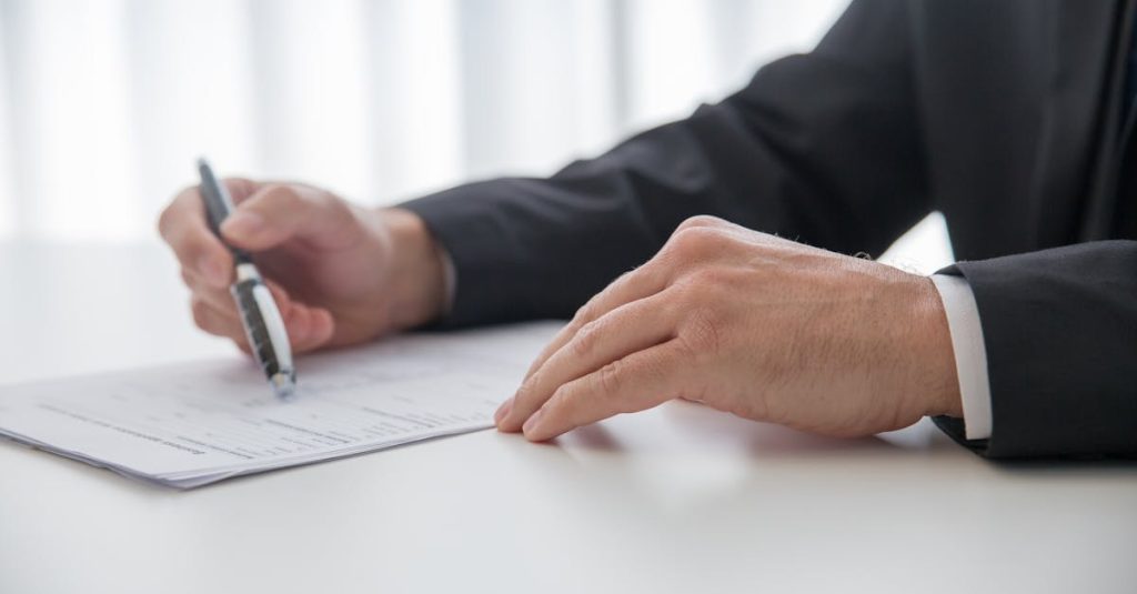 Businessman signing important documents at office desk.